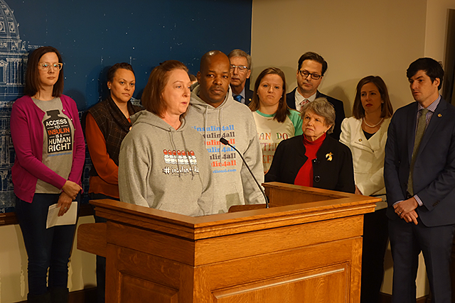 T1International Ambassador Nicole Smith-Holt speaking at podium and surrounded by other advocates and community members