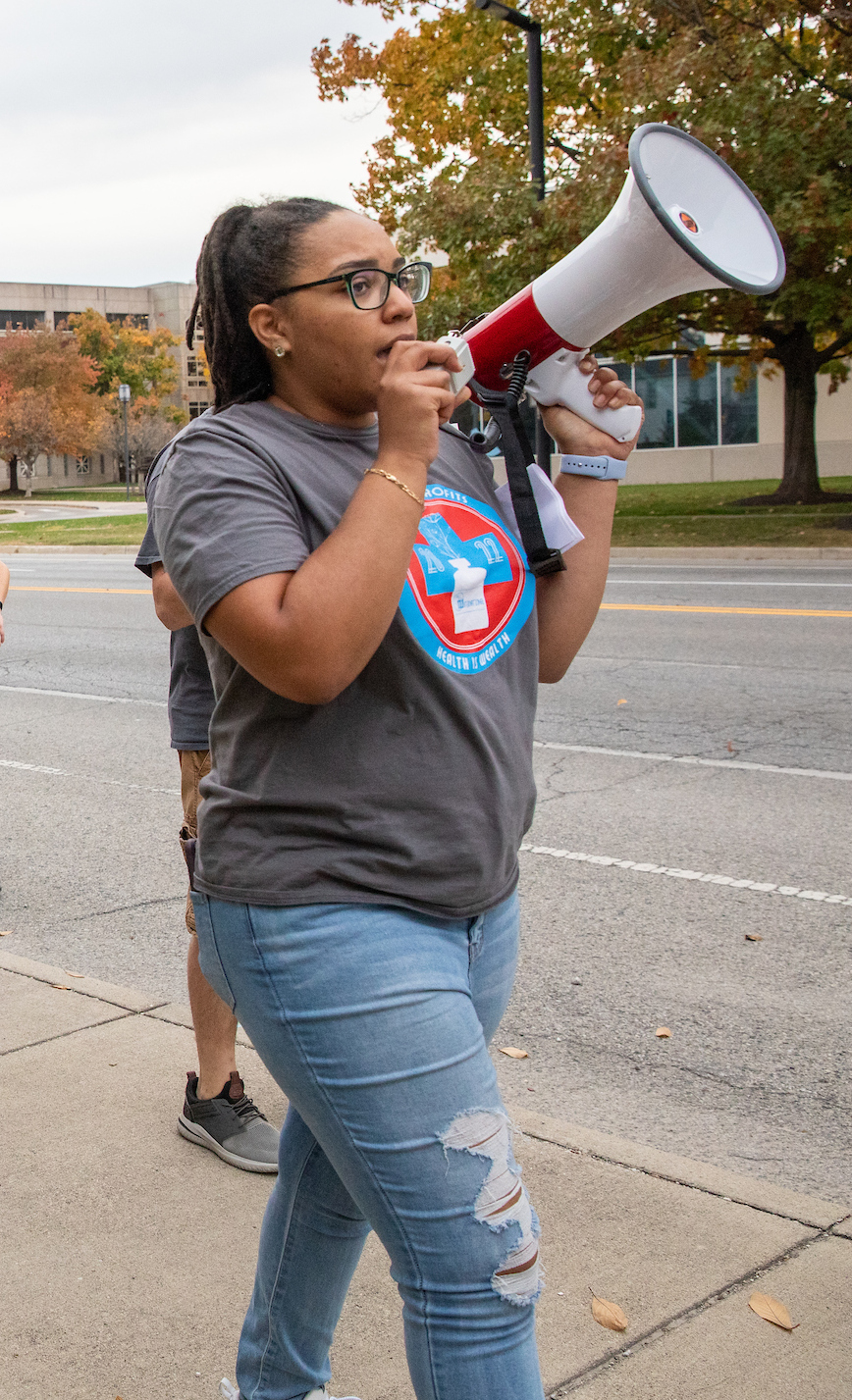 Sa'ra shouting into a microphone in a march