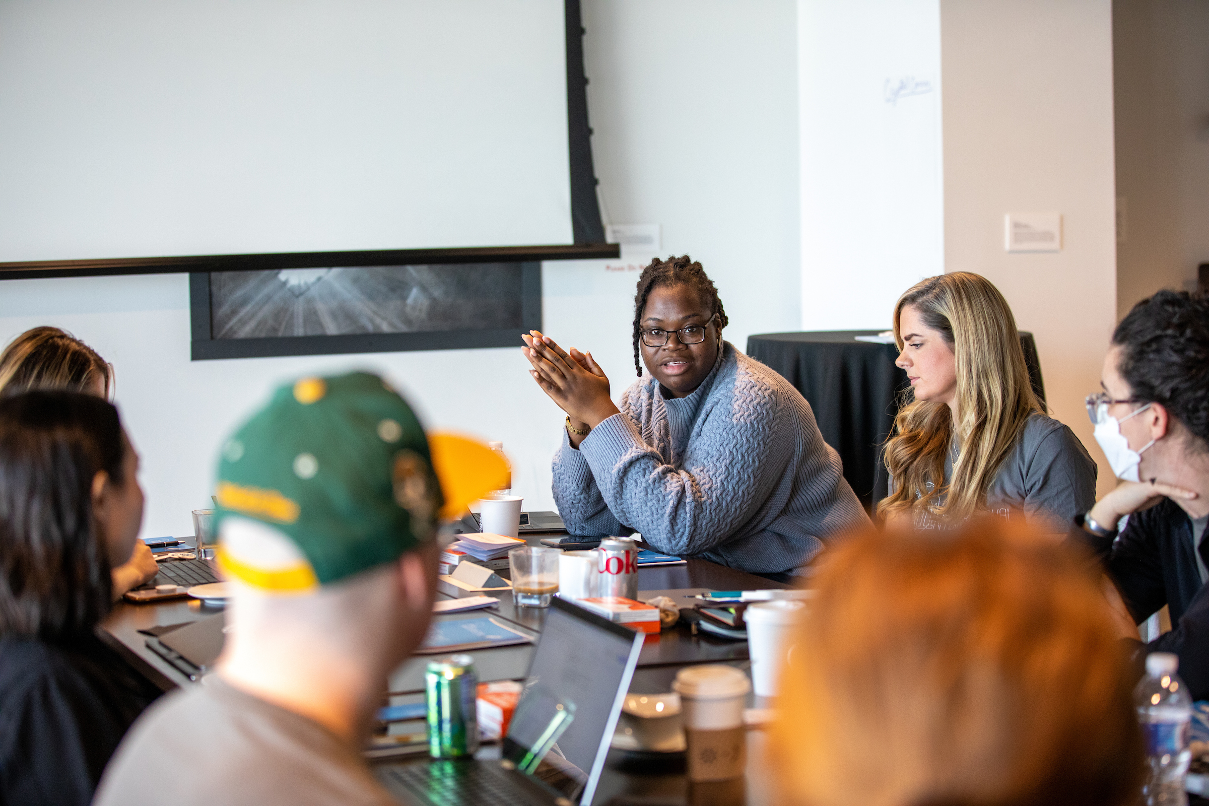 Faith, a black woman, is speaking at a table with other people. T1International team members meet for a conference and demonstration prep, at the Alexander Hotel in Indianapolis, IN on Sunday, October 23, 2022. © Photo by Erin Lubin