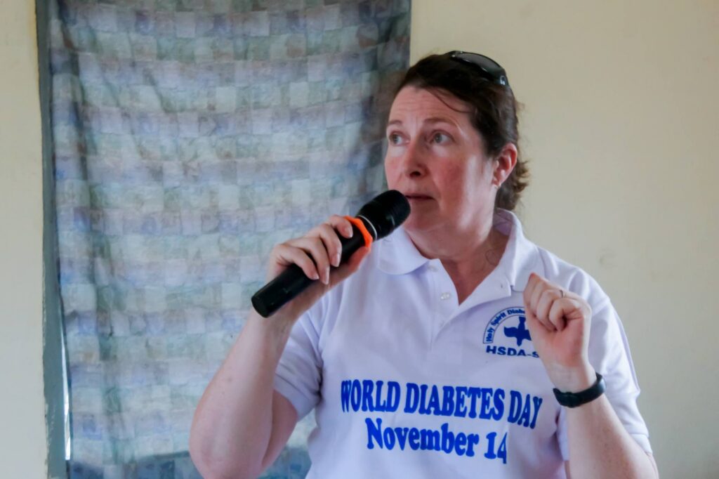 Photo of volunteer with Help Madina speaking into a microphone with a WDD shirt on in 2025