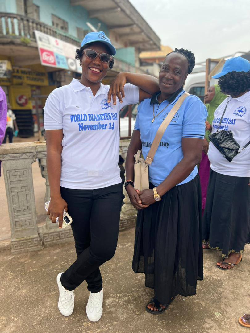 Two people in world diabetes day shirts and hats pose - Help Madina WDD 2025