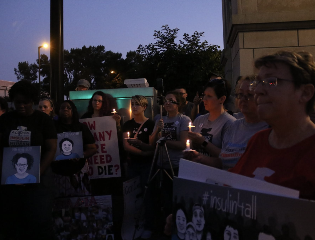 a dark photo of advocates at a vigil with candles