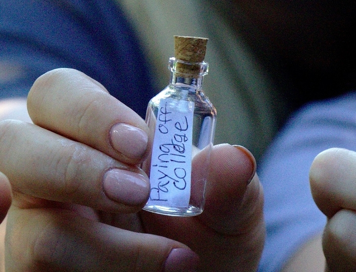 hands holding a vial saying "Paying off College"