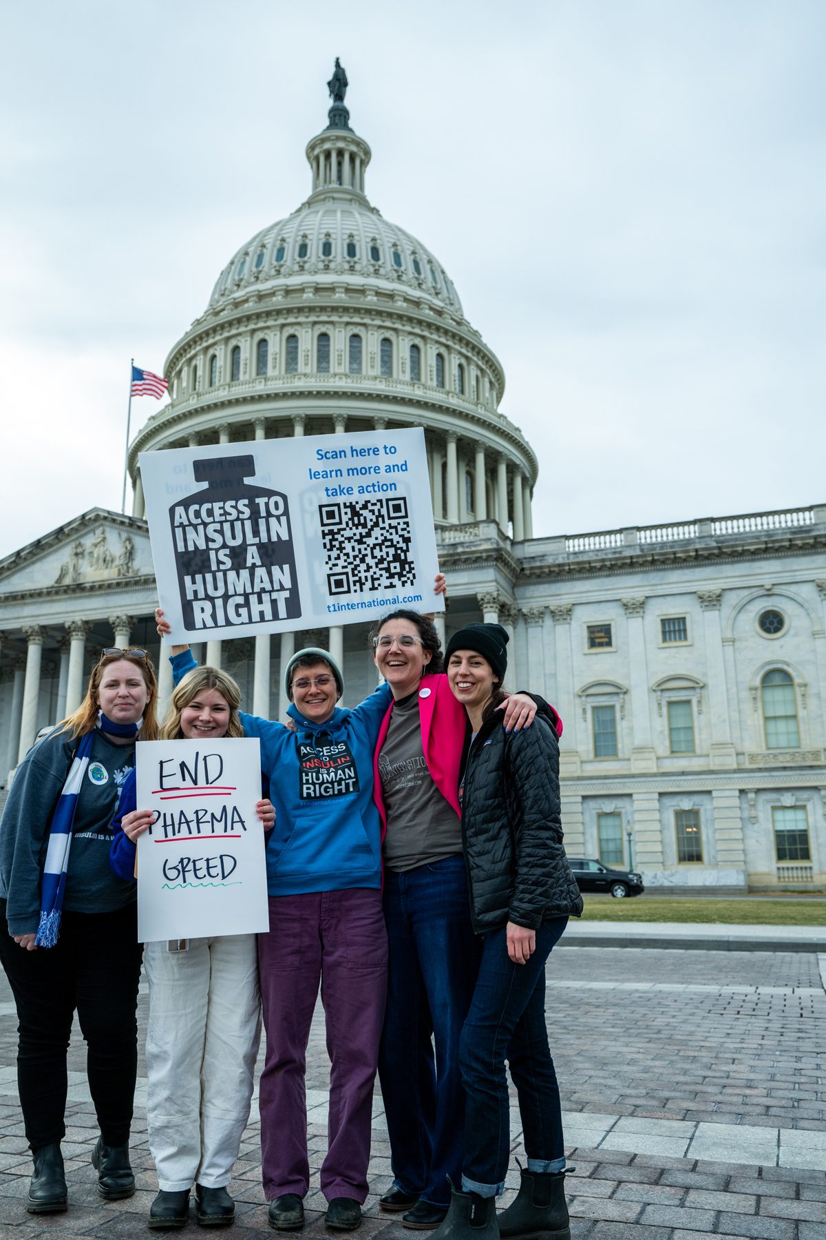 Four T1International advocates outside the US Capitol holding “End pharma greed” and “Access to insulin is a human right” signs
