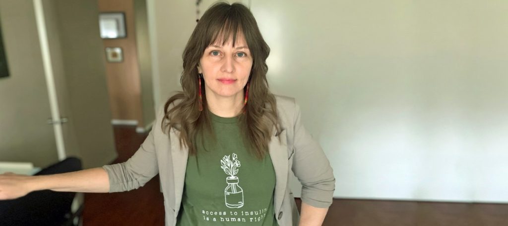 Staci Golar, a white woman in a green insulin shirt, faces the camera