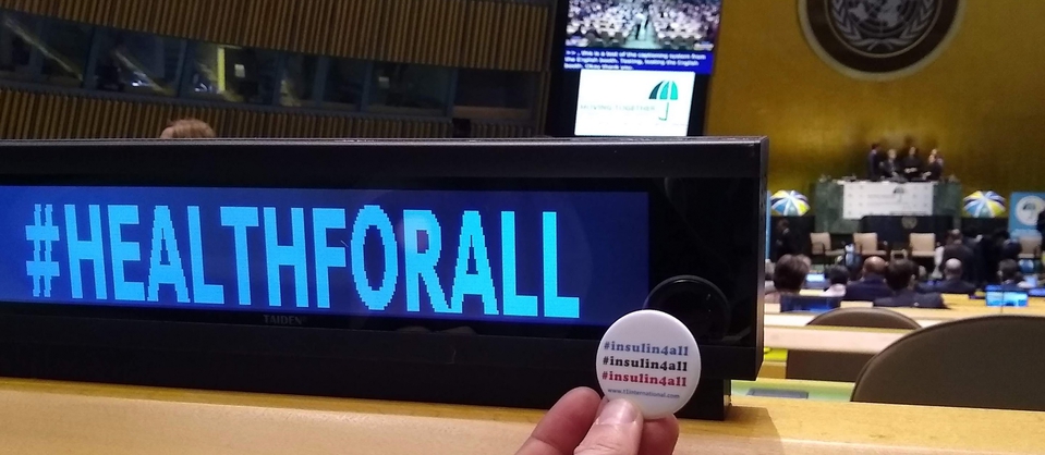 an insulin4all button is held up next to the hashtag healthforall at the UHC Hearing in the UN